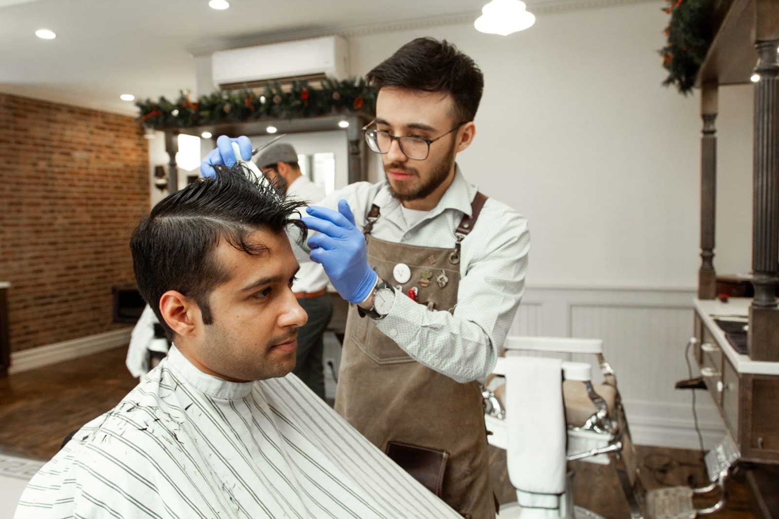 Barbeiro a terminar o corte de um cliente na barbearia